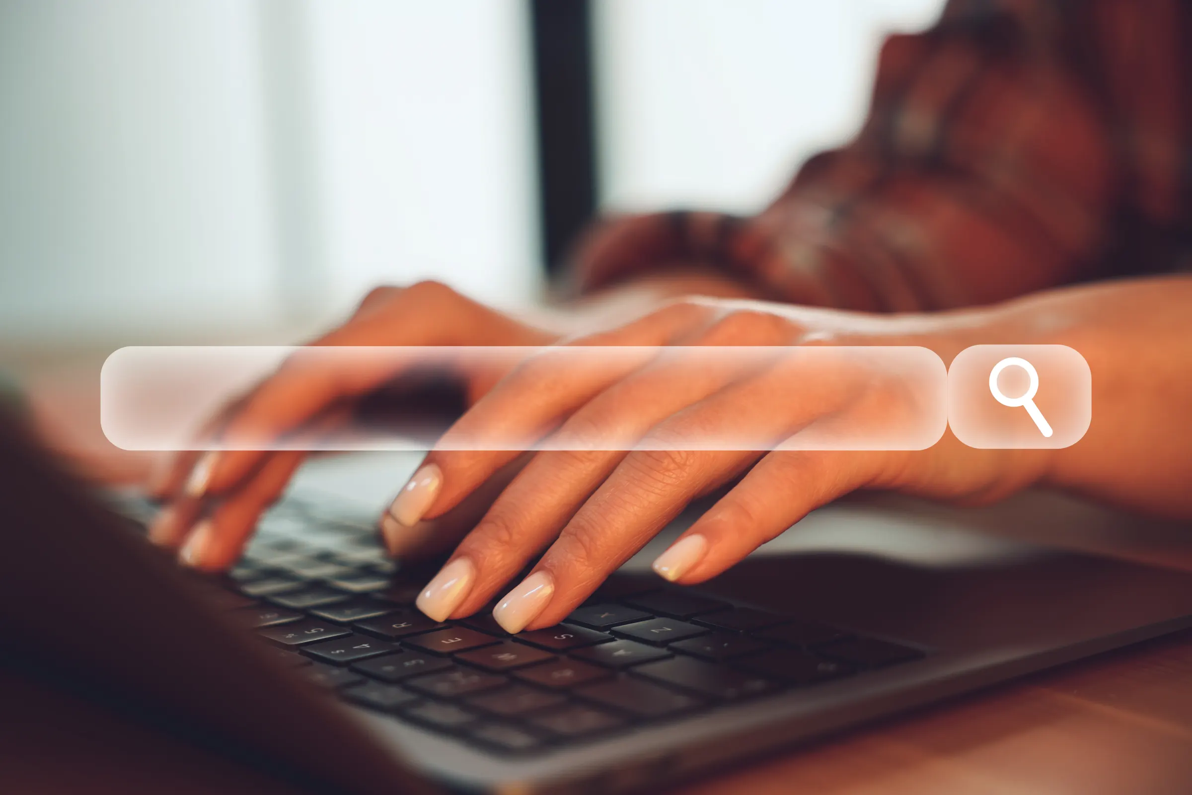 Hands typing a search on a laptop